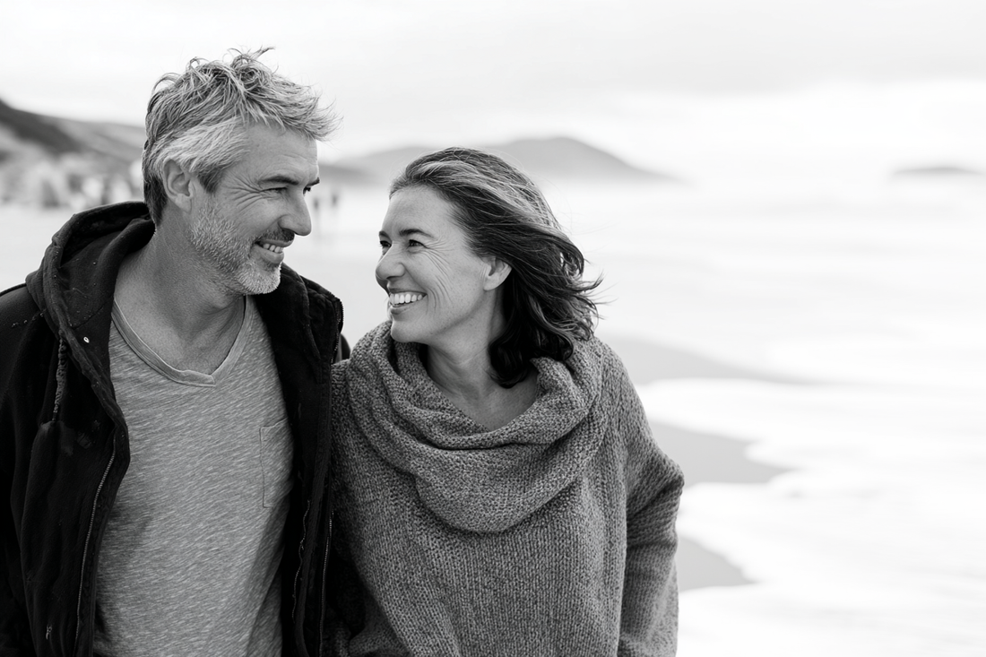 man and woman walking down the beach in new zealand